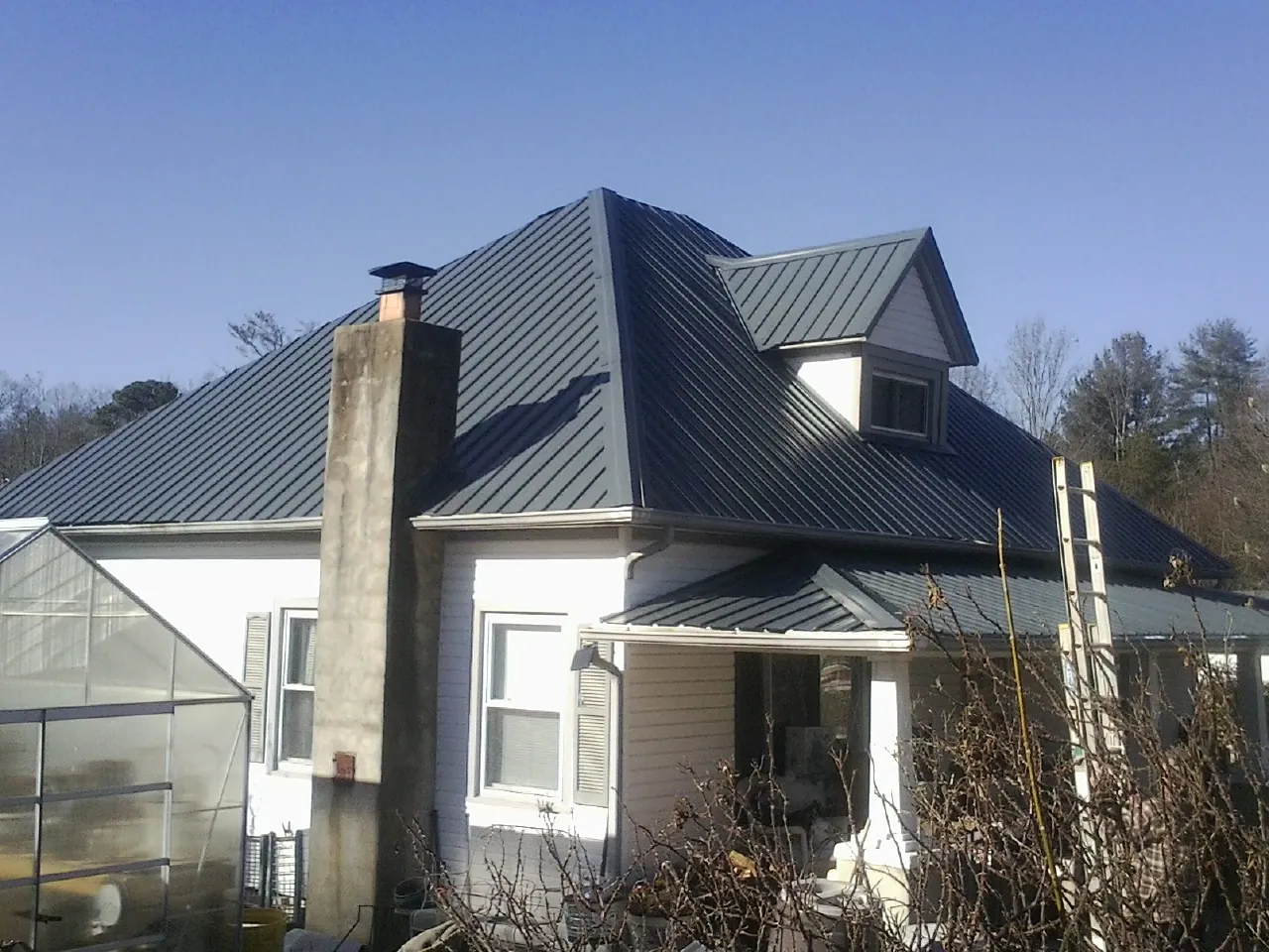 Dark blue standing seam metal roof on a white farmhouse with dormer — Slate & Tile Roof Repair by Roofing Brothers in Mount Pleasant Mills