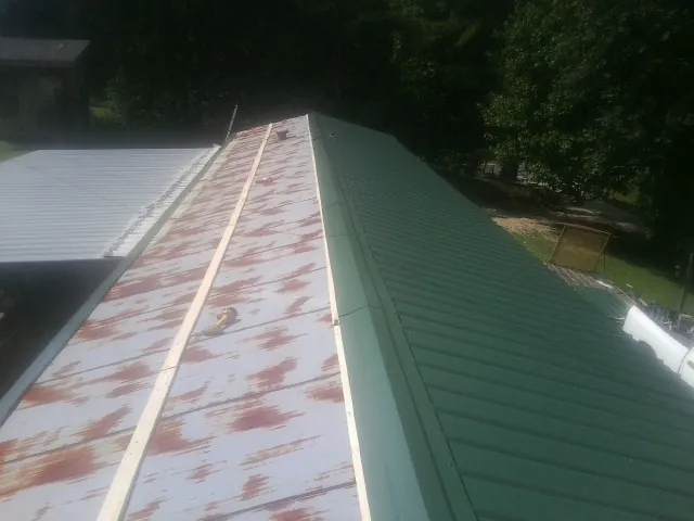 Old rusted panels beside newly installed green metal roofing — Wind Damage Roof Repair by Roofing Brothers in Mount Pleasant Mills
