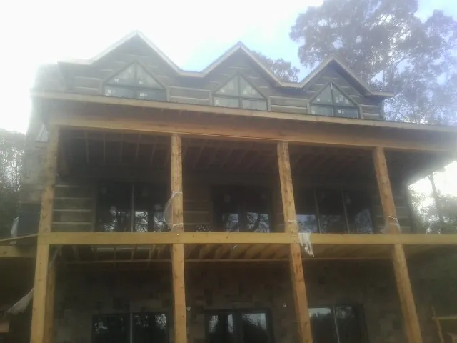 Dormers and porch framing on a large log home under construction — Roof Coating work by our crew in Mount Pleasant Mills