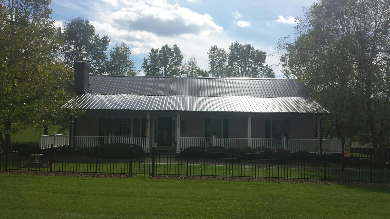 Gray metal roof on a brick ranch with a full width front porch — Gutter Guard Installation work by our crew in Mount Pleasant Mills