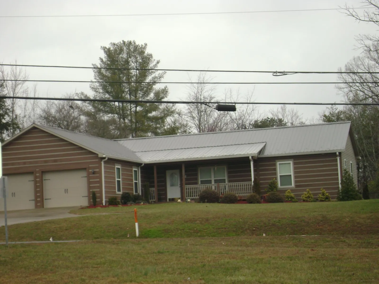 Gray metal roof on a log sided ranch home with a front porch in Mount Pleasant Mills