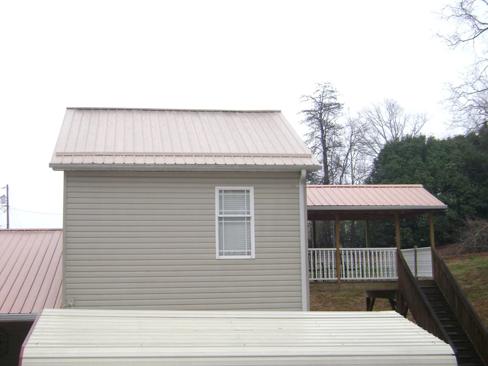 Tan metal roofs on a two story addition and attached porch, from a Roof Replacement job in Mount Pleasant Mills