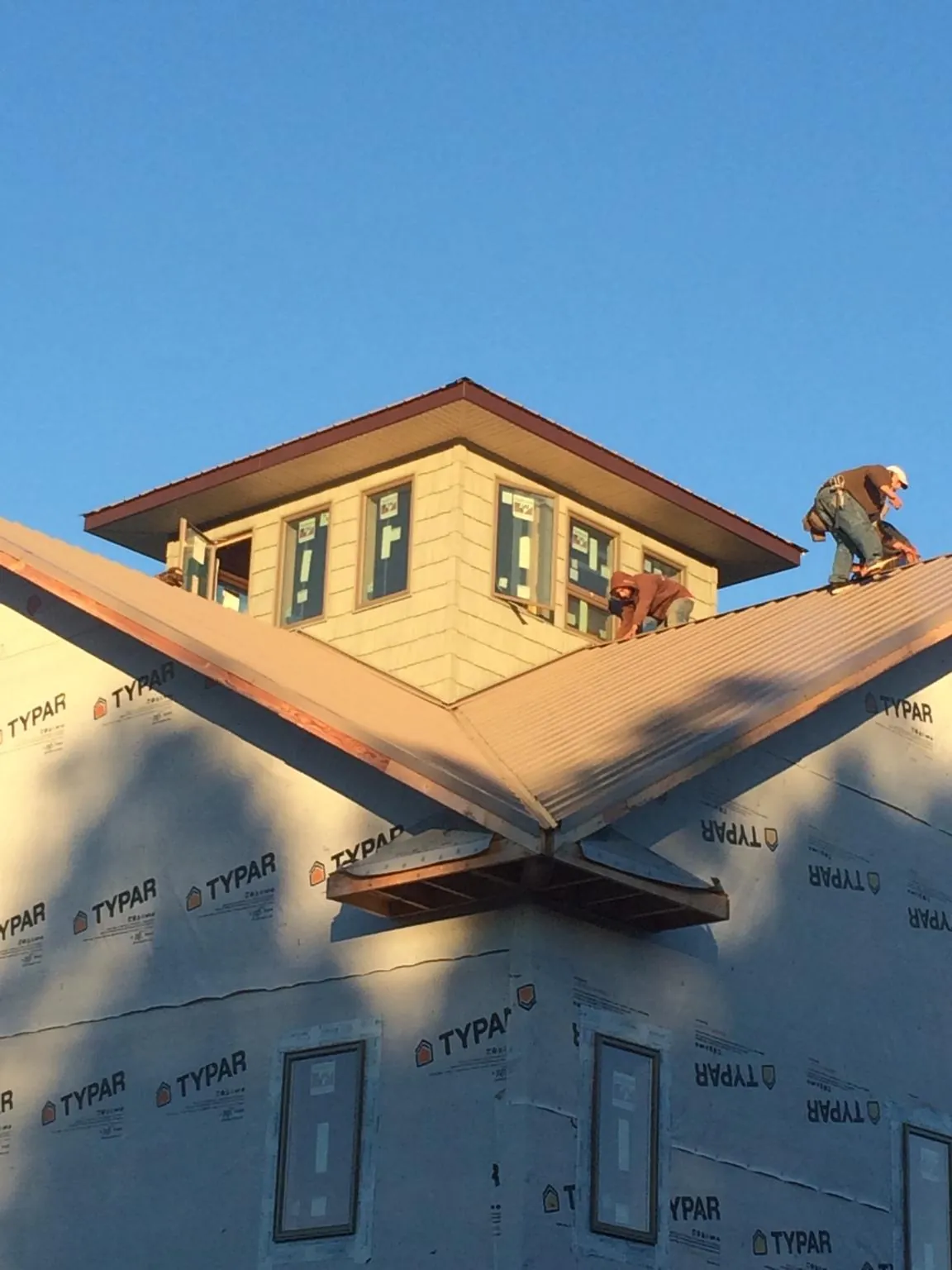 Roofers working around a rooftop cupola on a new metal roof at sunset — Roof Waterproofing in Mount Pleasant Mills by Roofing Brothers